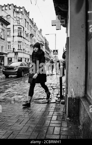 Marche sur le trottoir. Lviv/Ukraine - 30 janvier 2020 : une jeune fille se lance quelque part le long du trottoir humide de la rue Doroshenka. Banque D'Images