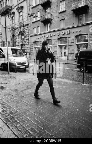 Parler en déplacement. Lviv/Ukraine - 30 janvier 2020: Une fille marchant dans la rue Akademika Hnatyuka parlant au téléphone Banque D'Images