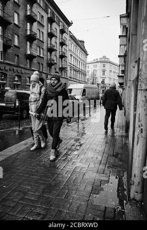 Marcher ensemble. Lviv/Ukraine - 30 janvier 2020 : couple tenant les mains marchant dans la rue Akademika Hnatyuka Banque D'Images