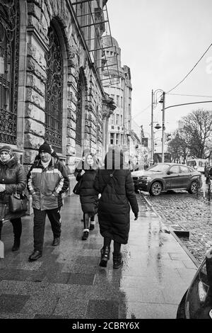 Les passants de Lviv - en marchant le long de l'avenue. Lviv/Ukraine - 30 janvier 2020: Les gens marchent dans le trottoir humide sur le Prospect Svobody. Banque D'Images