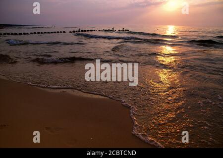 Coucher de soleil au bord de la mer. Soleil rouge flamboyant au-dessus des vagues de fond. Banque D'Images