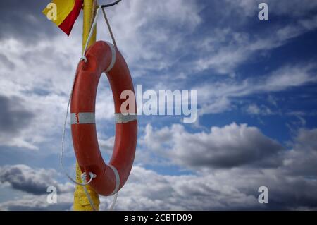 Une bouée de sauvetage sur la plage au fond des nuages et du ciel. Sécurité pendant vos vacances en bord de mer. Anneau de secours orange. Banque D'Images