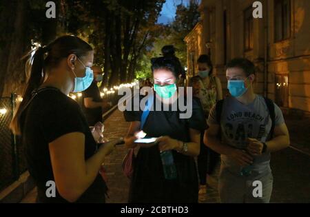 Bucarest, Roumanie. 15 août 2020. Les résidents ayant un masque facial présentent leurs billets numériques avant d'entrer dans un cinéma en plein air à Bucarest, Roumanie, le 15 août 2020. Le gouvernement roumain maintient la fermeture des cinémas et des théâtres dans le contexte de la pandémie COVID-19, mais permet des films ou des spectacles en plein air avec un public limité et des réglementations de prévention des épidémies. Credit: Gabriel Petrescu/Xinhua/Alay Live News Banque D'Images