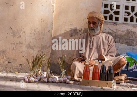 Un homme omanais qui vend du miel et de l'ail au souq de Nizwa Banque D'Images