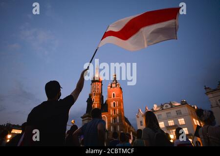 Cracovie, Pologne. 15 août 2020. Un manifestant détient un drapeau d'opposition biélorusse blanc-rouge-blanc pendant la manifestation. Des centaines de bélarussiens vivant à Cracovie et des supporters locaux se sont réunis lors du rassemblement de solidarité organisé sur la place du marché de Cracovie, à l'extérieur du monument Adam Mickiewicz, contre le leader bélarussien, Alexandre Loukachenko. Crédit : SOPA Images Limited/Alamy Live News Banque D'Images