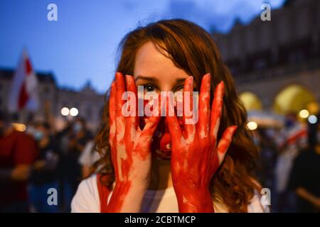 Cracovie, Pologne. 15 août 2020. Un manifestant montre de fausses mains « sanglantes » rouges pendant la manifestation.des centaines de bélarussiens vivant à Cracovie et des supporters locaux se sont rassemblés pendant le rassemblement de solidarité organisé sur la place du marché de Cracovie, à l'extérieur du monument Adam Mickiewicz contre le dirigeant bélarussien, Alexander Lukashenko. Crédit : SOPA Images Limited/Alamy Live News Banque D'Images