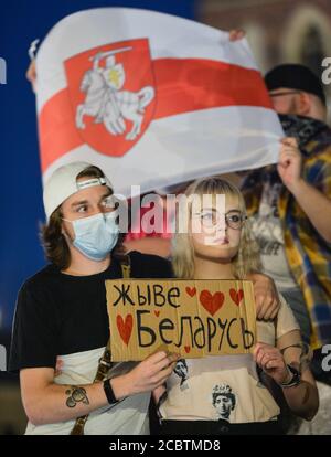 Cracovie, Pologne. 15 août 2020. Un couple tient des drapeaux d'opposition biélorusses blancs-rouges-blancs pendant la manifestation.des centaines de biélorusses vivant à Cracovie et des supporters locaux se sont réunis pendant le rassemblement de solidarité organisé sur la place du marché de Cracovie, à l'extérieur du monument Adam Mickiewicz contre le dirigeant biélorusse, Alexander Lukashenko. Crédit : SOPA Images Limited/Alamy Live News Banque D'Images