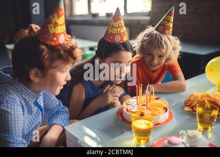 Trois enfants regardent le gâteau et se sentent excités Banque D'Images