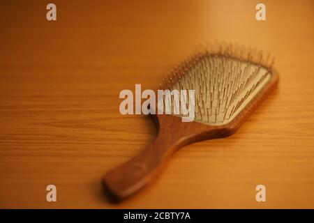 Femme peignant les cheveux longs blonds avec peigne en bois de pelle gros plan Banque D'Images