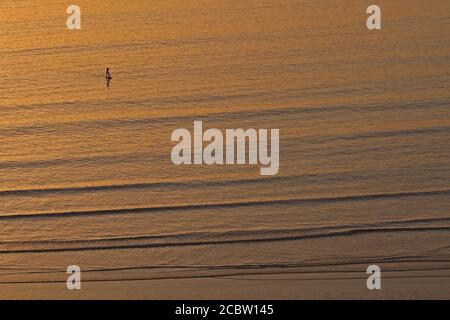 Une paddle-boardeur passe dans les eaux calmes de la baie de Rhossili, dans le Gower South Wales, lors d'une belle soirée au coucher du soleil du 12 août 2020. ©PRWPhotog Banque D'Images