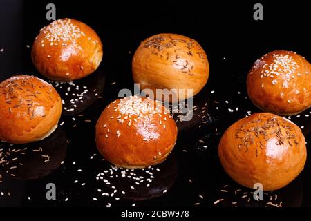 Petits pains blancs croustillants aux graines de sésame. Photo sur fond noir. Banque D'Images