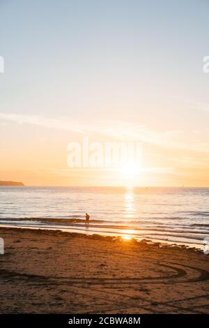 Magnifique coucher de soleil sur une plage à la mer Baltique avec la silhouette d'un baignant Banque D'Images