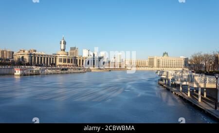 Tianjin / Chine - 14 février 2016 : fleuve Hai gelé (Haihe) dans le centre de Tianjin, avec la gare de Tianjin en arrière-plan Banque D'Images