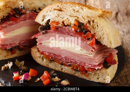 Un authentique sandwich Muffuletta de la Nouvelle-Orléans rempli de salade d'olives, fromage, salami et jambon sur une table en ardoise. Horizontale Banque D'Images