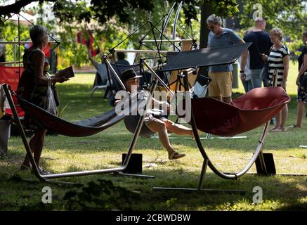 Hanovre, Allemagne. 16 août 2020. Les visiteurs se détendent dans des hamacs au Herrenhausen Garden Festival à Hanovre. Le festival de Georgengarten à Hanovre, initialement reporté aux jours de Whitsun, a attiré de nombreux visiteurs le week-end par temps chaud en été. Les exposants ont présenté des offres pour la conception de jardin, de nombreuses plantes et décorations différentes. En outre, il y avait beaucoup à manger et à boire ainsi que des conseils pour les amoureux du jardin. Credit: Peter Steffen/dpa/Alay Live News Banque D'Images