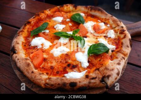 Gros plan de Pizza Margherita sur la table de wodden. Pizza Margarita typiquement italienne maison avec tomates, basilic et fromage mozzarella. Banque D'Images