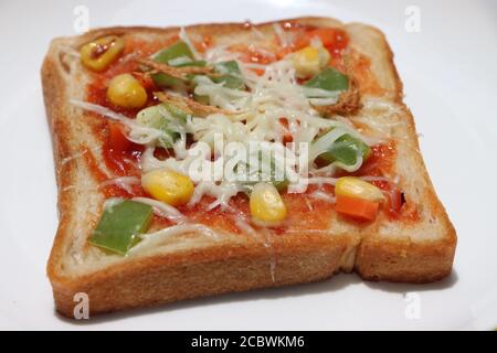 Pizza au pain brun, garnie de maïs doux, de légumes et de fromage, petit déjeuner pour les enfants, cuisine indienne de rue Banque D'Images