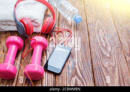 haltères et une bouteille d'eau avec une serviette sur fond de bois, concept de préparation à l'équipement de sport de fitness vue de dessus. Casque et téléphone. Musique Banque D'Images