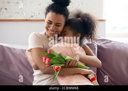 Bonne mère noire embrassant la fille recevoir des félicitations pour la fête des mères Banque D'Images