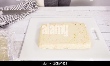 Étape par étape. Coupe de fudge de canne à sucre fait maison sur un tableau de découpe blanc. Banque D'Images