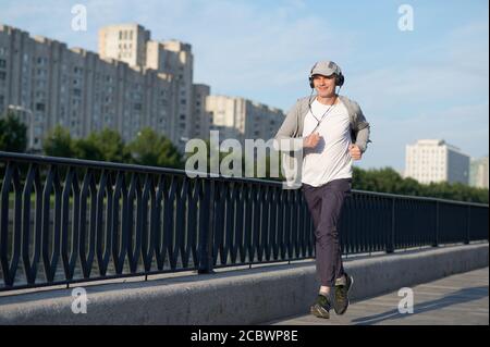 Homme caucasien mature avec écouteurs de jogging dans la ville Banque D'Images