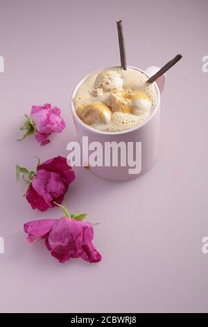 Café glacé avec glace au chocolat et bâtonnets de chocolat une tasse rose décorée de fleurs de rosehip Banque D'Images