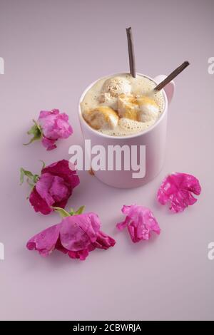 Café glacé avec glace au chocolat et bâtonnets de chocolat une tasse rose décorée de fleurs de rosehip Banque D'Images