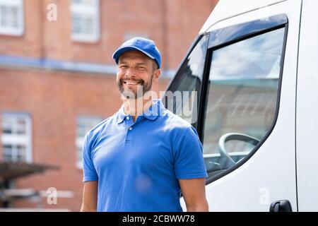 Souriant livraison hommes ou homme à la main en uniforme près du camion Banque D'Images