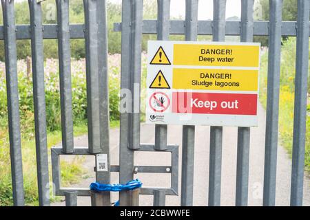 Porte verrouillée avec divers avertissements de danger près d'une installation de traitement d'eau United Utilities sur Red Rock Lane, Stoneclough, Angleterre, Royaume-Uni Banque D'Images