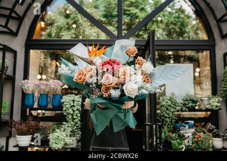Livraison de fleurs et fleuriste avec son travail. Femme tenant beau bouquet multicolore Banque D'Images