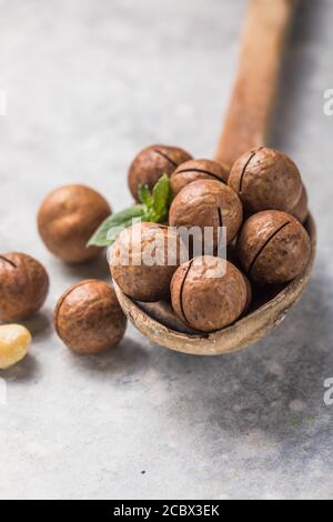 Empiler les noix de macadamia ouvrir les noyaux et les coquilles dans la cuillère sur fond de pierre. Banque D'Images