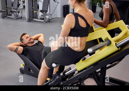 fit filles soutien sportif whie il fait des exercices sur l'équipement. homme pump jambes, dans la salle de gym moderne Banque D'Images