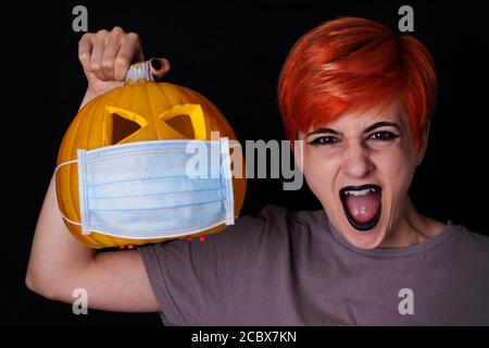 crier fille avec citrouille avec masque facial - halloween dedans l'âge du coronavirus Banque D'Images