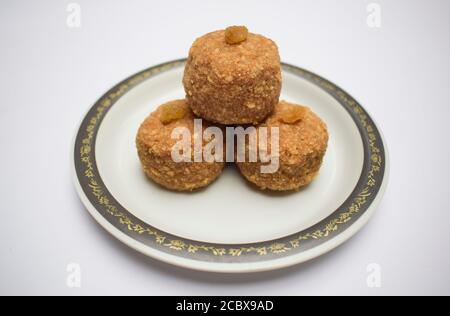 Gros plan des boules sucrées indiennes populaires Laddu ou ladoo fait de chapati roti poudre en purée et fait dans le grand ballon. Décor avec service de kismis aux raisins secs Banque D'Images