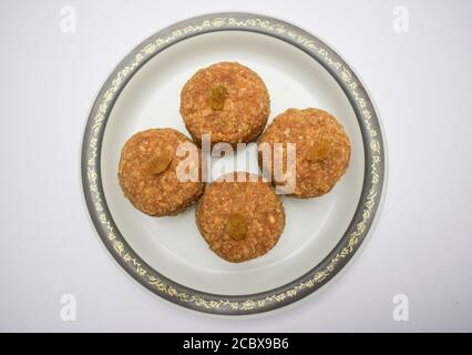 Gros plan des boules sucrées indiennes populaires Laddu ou ladoo fait de chapati roti poudre en purée et fait dans le grand ballon. Décor avec service de kismis aux raisins secs Banque D'Images