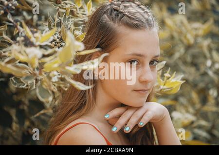 belle jeune fille dans une robe rouge sur un fond de feuillage. citron vert tonifiant Banque D'Images