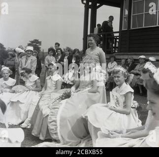 1950s. Historique, récemment couronnée Rose Queen assise dans sa robe avec d'autres filles et regardée par la population locale, Farnworth, Lancashire, Angleterre, Royaume-Uni. Remontant aux années 1880, le festival annuel de la Reine des roses se tenait traditionnellement au mois de juin, devenant un événement annuel dans de nombreuses villes et villages du Royaume-Uni, en particulier dans le comté de Lancashire, connu sous le nom de comté de la Rose Rouge, après les guerres des Roses (1455-87). Banque D'Images