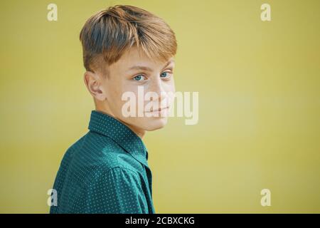 jeune homme dans une chemise bleue avec les yeux bleus un arrière-plan jaune Banque D'Images
