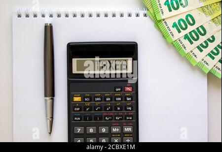 Calculatrice avec inscription « taxes », note blanche, billets en euros, stylo. Concept d'entreprise. Magnifique arrière-plan blanc, espace de copie. Banque D'Images