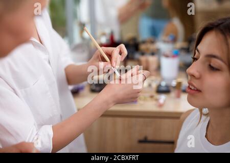 un maquilleur professionnel ou un visagiste applique des cosmétiques à portée de main avant de les appliquer sur le visage, dans un salon de beauté Banque D'Images