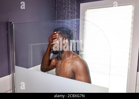 beau skined sombre homme prenant la douche dans la salle de bains, homme détendu profiter de passer du temps dans le bain le matin Banque D'Images