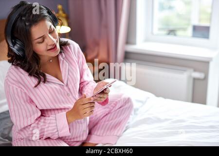 femme enceinte chantant ses chansons préférées avec de la musique acclamée tout en étant assise à la maison le matin, adorable femme dans le casque d'écoute profiter de l'expectine Banque D'Images