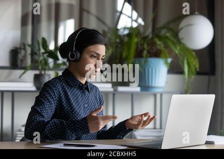 Femme sérieuse de race mixte impliquée dans la pratique de la langue étrangère en ligne. Banque D'Images