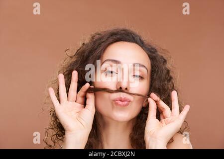 Jeune femme drôle brunette avec les yeux fermés ayant le plaisir avec bouquet de cheveux Banque D'Images