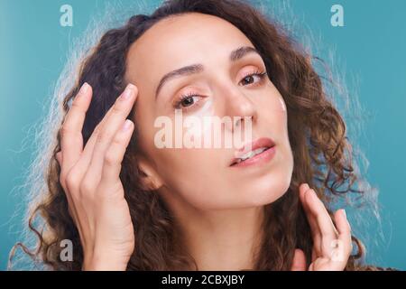 Jeune femme brune magnifique avec des taches sous les yeux touchant le temple Banque D'Images