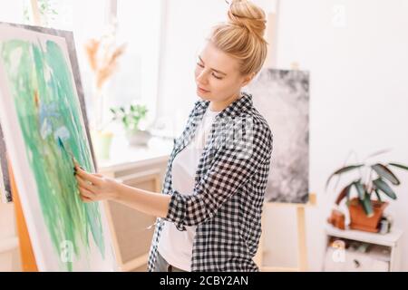 Photo d'artiste féminine à l'aide d'une spatule en atelier. Gros plan sur la photo de côté. Temps libre, temps libre Banque D'Images