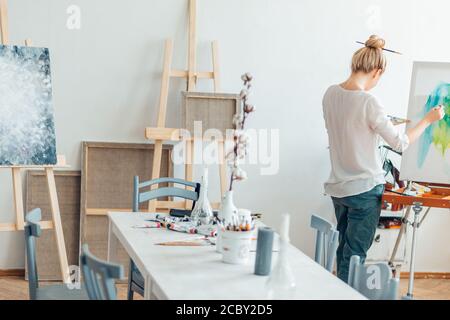 salle lumineuse pour la peinture . femme debout sur le coin de la salle en face du chevalet Banque D'Images