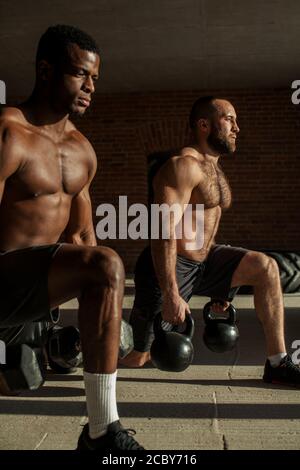 Le sport, mode de vie et de personnes concept crossfit - deux jeunes athlètes masculins de race blanche et de l'Afrique avec des fentes avec haltères en poids d'entraînement intérieure Banque D'Images