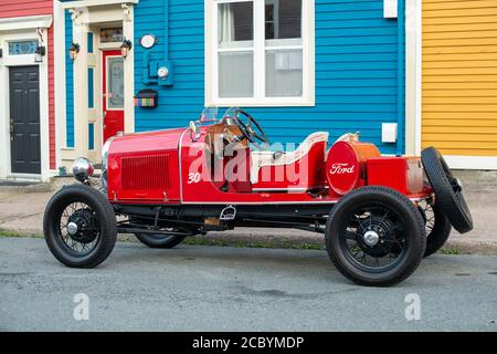 Un modèle UNE voiture Ford est inactive à l'extérieur de plusieurs maisons de rangée colorées dans le centre-ville de St. John's. La voiture est rouge vif avec des pneus noirs et un intérieur marron clair. Banque D'Images