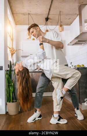 joyeux jeune couple caucasien dansant à la maison, ils ont des relations harmonieuses, passer du temps libre les uns avec les autres, profiter d'être à la maison Banque D'Images